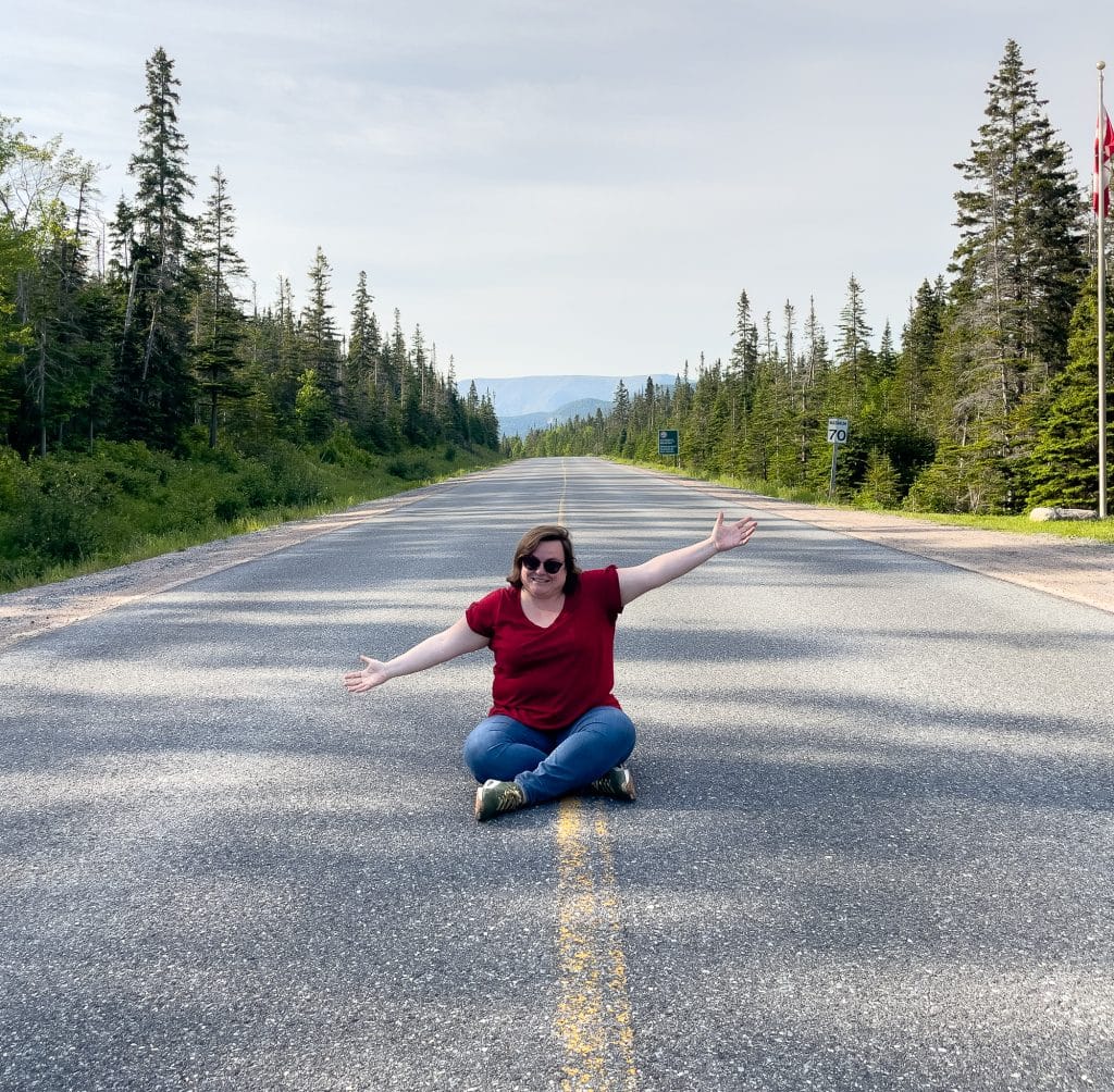 Jennifer assise sur la ligne jaune du Parc national du Gros-Morne